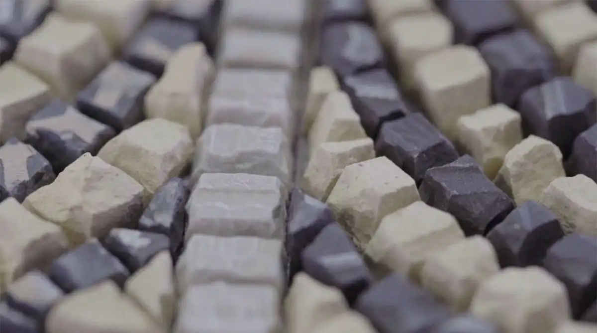 Close-up of a textured surface with alternating rows of light and dark rectangular stones.