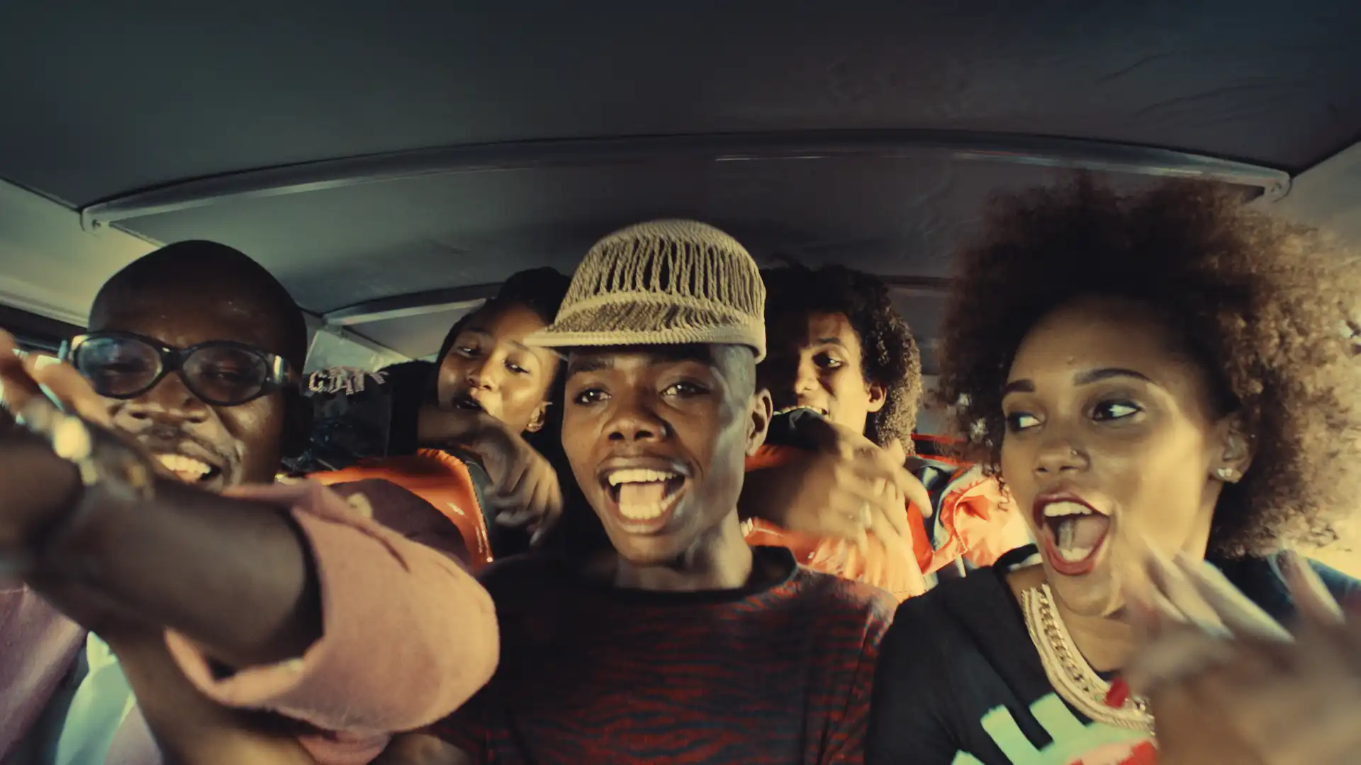 Group of friends joyfully singing and dancing inside a car, creating a lively and fun atmosphere.