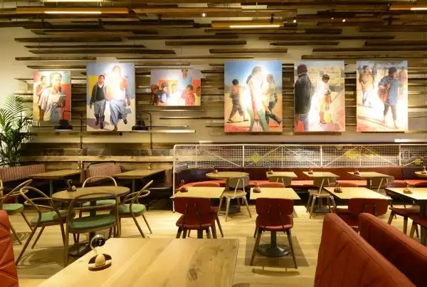 A vibrant Nando's restaurant interior with colorful artwork, wooden accents, and neatly arranged tables and chairs.